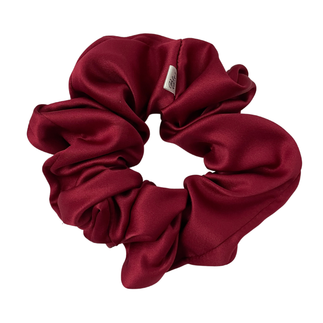 A matte red satin scrunchie displayed on a white background.