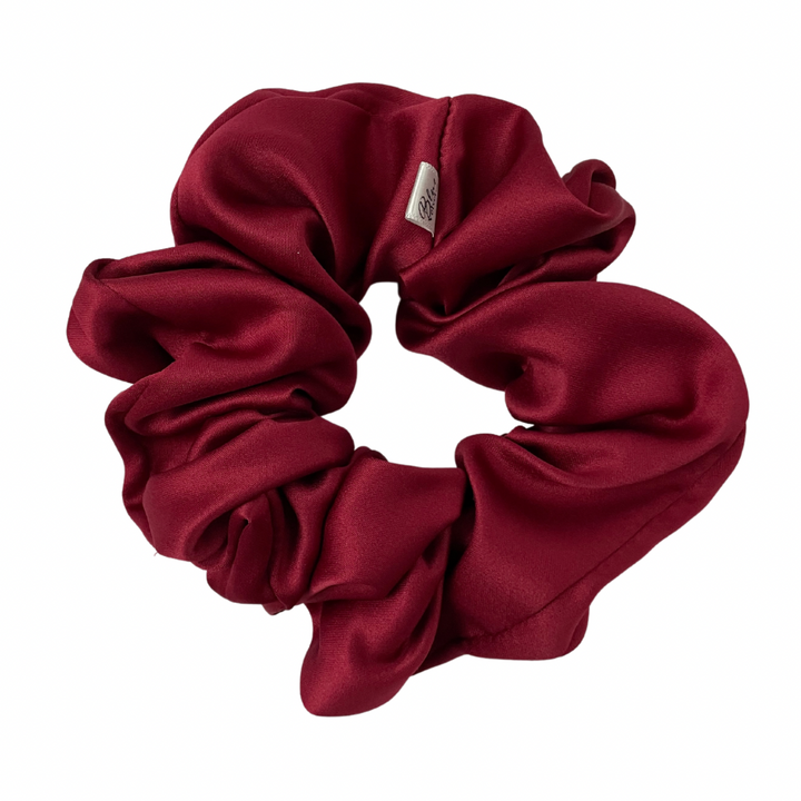 A matte red satin scrunchie displayed on a white background.