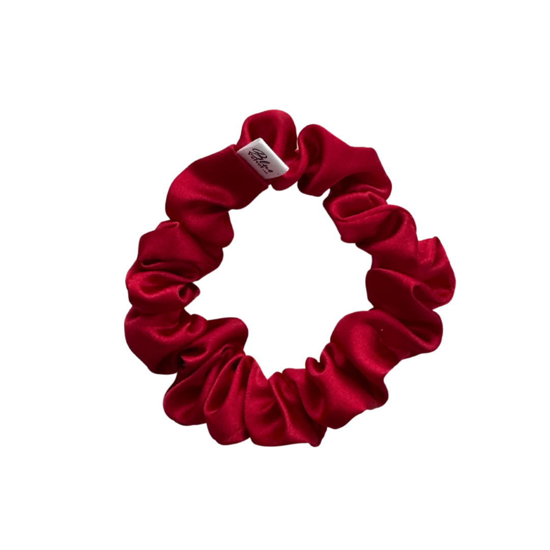 A red satin scrunchie on a white background.