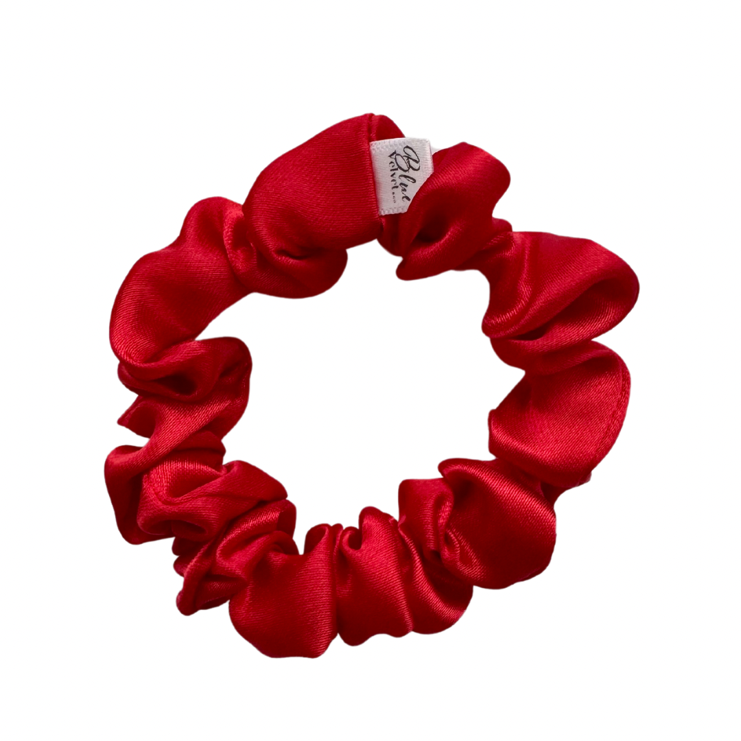 A bold red silky satin scrunchie against a white background.