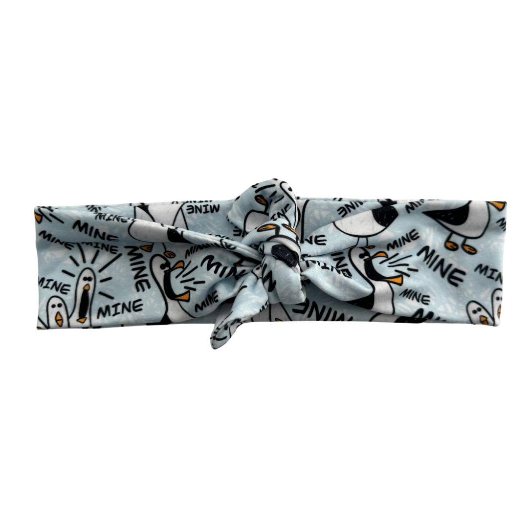 A tie headband with a pattern of birds and the text &