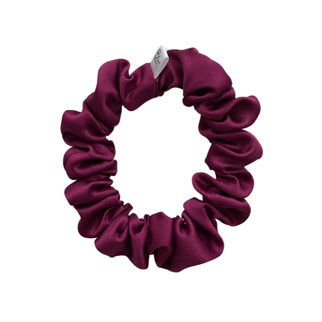 A purple matte satin scrunchie on a white background.