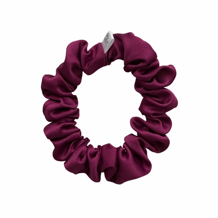 A purple matte satin scrunchie on a white background.