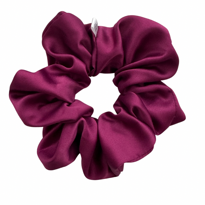 A matte purple satin scrunchie displayed against a white background.
