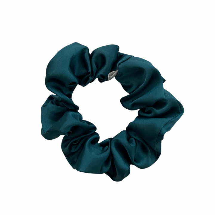 A deep teal satin scrunchie isolated on a white background.