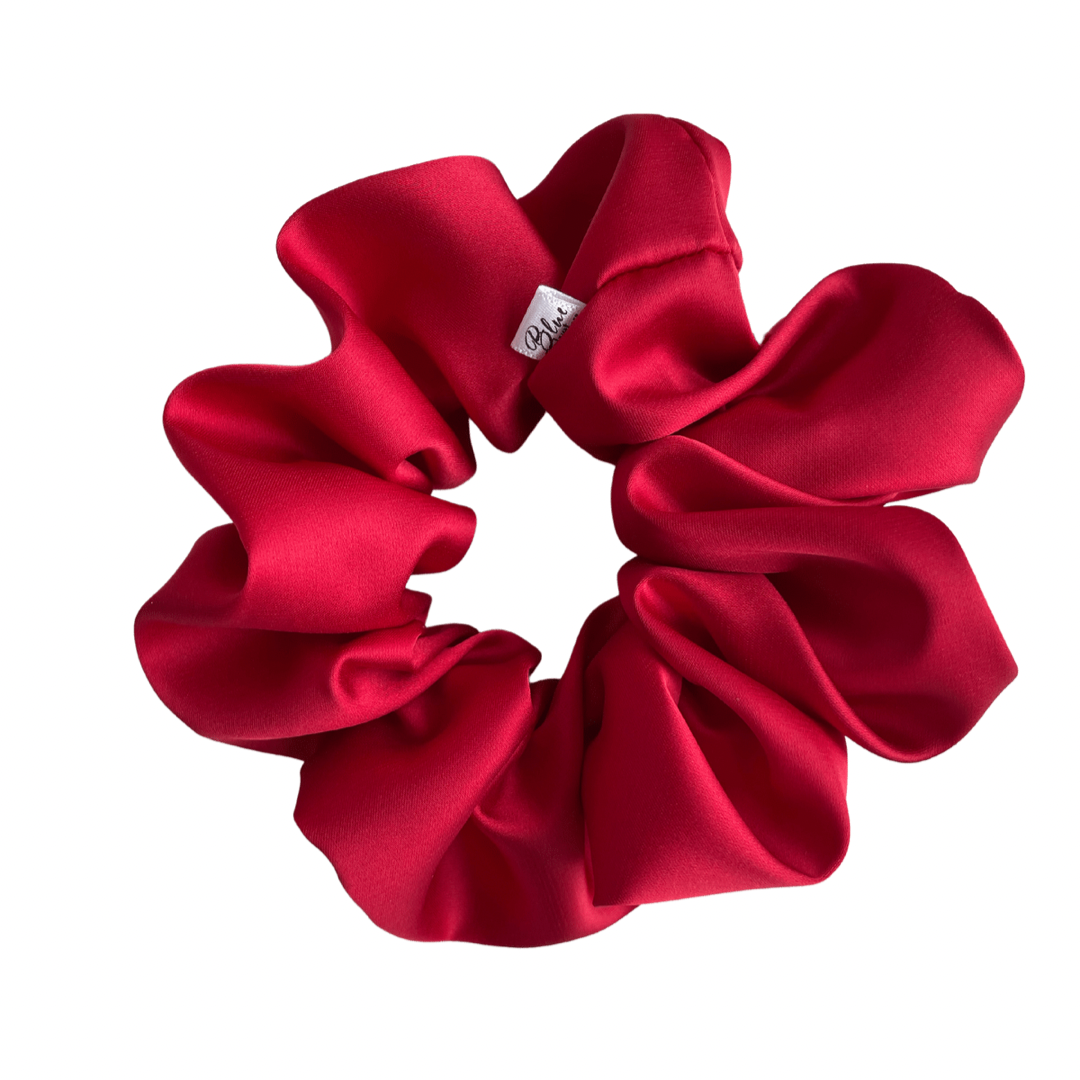 A matte red satin scrunchie displayed on a white background.