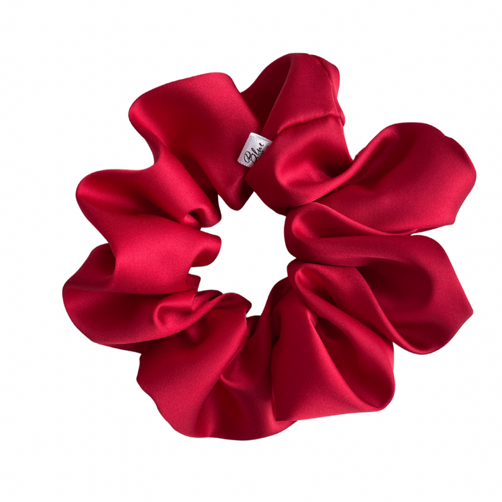 A matte red satin scrunchie displayed on a white background.